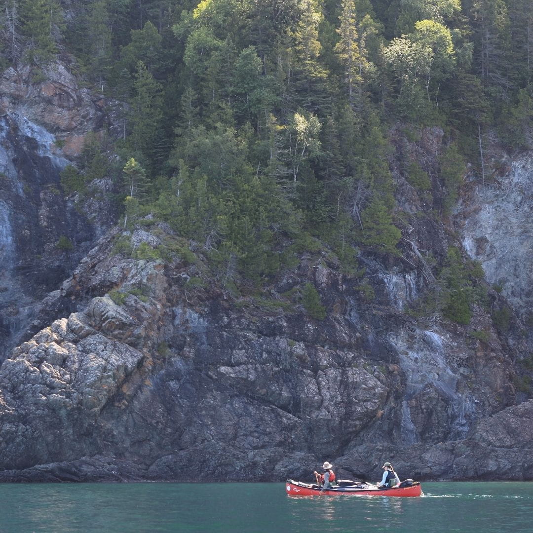 Expédition en canot sur les Grands Lacs Canot double rouge avec toile de pontage navigant sur les eaux turquoises d'un lac